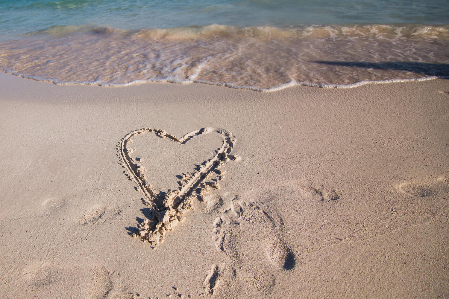 heart drawn in sand at beach